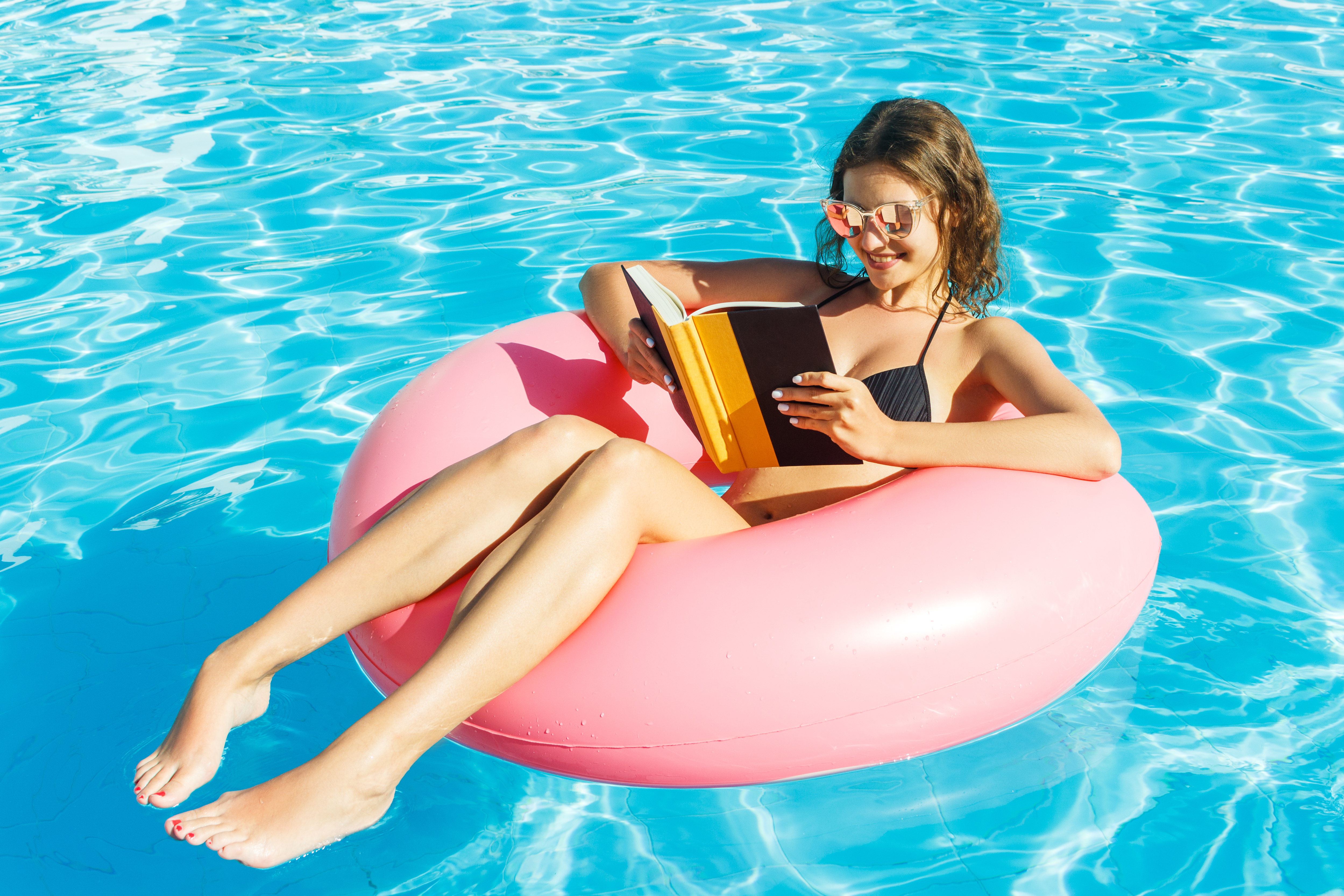 FEMME EN TRAIN DE LIRE DANS UNE PISCINE