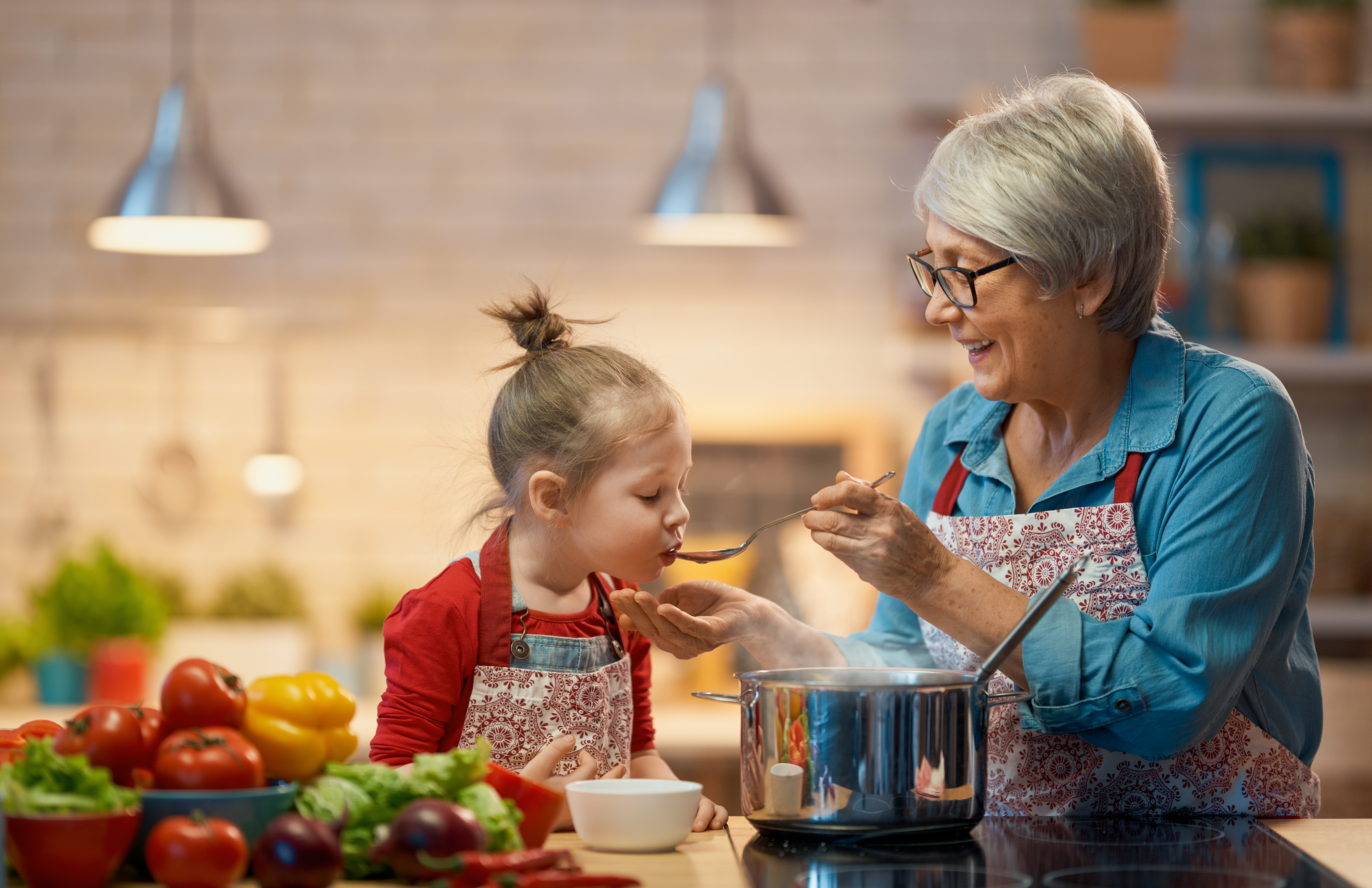 petite fille qui goûte à la cuillère un plat fait-maison préparé par sa grand-mère