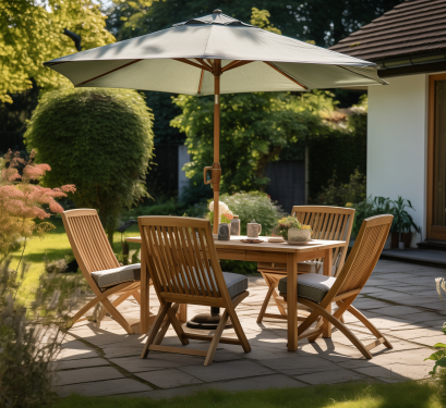 Terrasse de jardin aménagée avec une table et des chaises en bois sous un grand parasol, entourée de végétation et de fleurs, dans une ambiance estivale et chaleureuse.